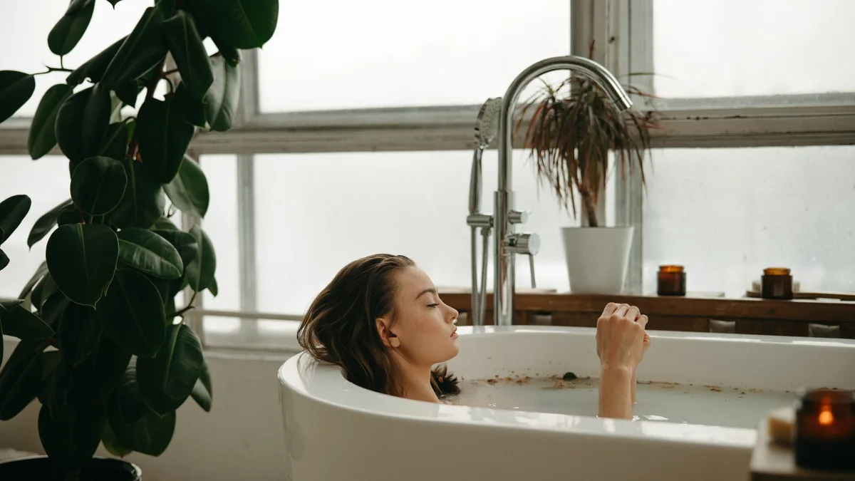 A woman peacefully soaking in a bathtub surrounded by plants and candles, embracing tranquility.